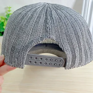 Détail de la casquette argentée en tricot montrant la fermeture réglable snapback