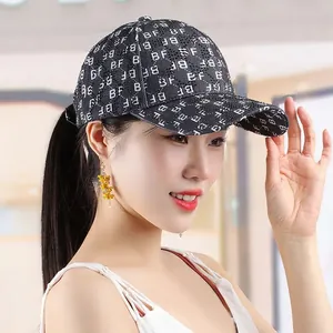 Detail view of black baseball cap with white letter prints on a female model