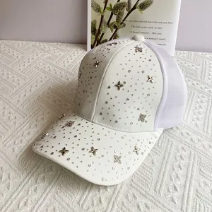 Detailed view of rhinestone lucky clover studs on white mesh baseball cap for women