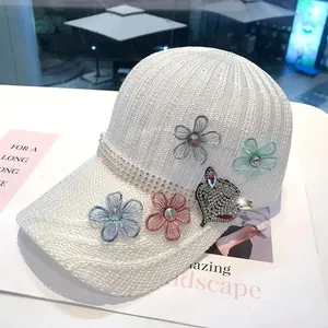 Dettagli con fiori ricamati e patch gatto in strass su berretto da baseball bianco