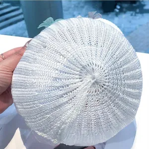 Dettaglio cappello bianco a maglia con trama in pizzo e farfalle in rete 3D