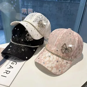Close-up of lace baseball caps in white, black and pink with rhinestone bows