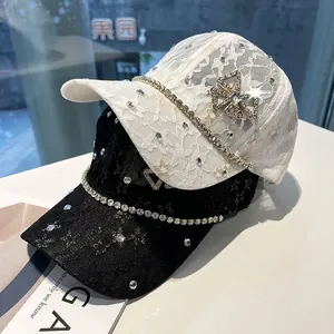 Detailed view of luxury lace baseball caps with rhinestones and metal clover emblems