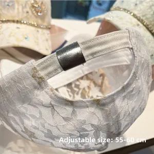 Dettaglio della fibbia regolabile su berretto in pizzo bianco con ricamo floreale