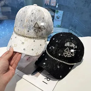 Detailed view of lace baseball caps in white and black with shiny rhinestone accents