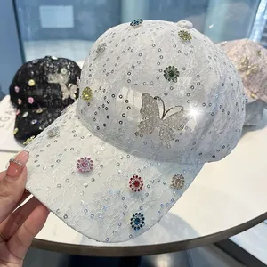 Detail der weißen Spitzen-Baseballkappe mit funkelnden Schmetterlingssteinen und Pailletten