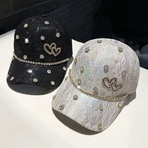 Close-up of lace baseball caps with rhinestones, double heart logo, and crystal chain trim