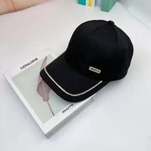 Detailed close-up of a black baseball cap featuring colorful rhinestones and a metal plate