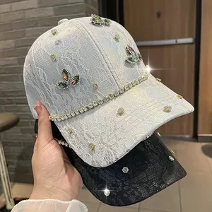 Dettaglio di berretti da baseball in pizzo con farfalle di strass e catene di cristalli
