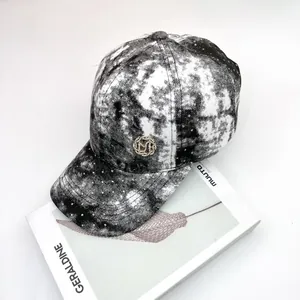 Detalle de gorra tie-dye con diamantes de imitación brillantes y escudo metálico sobre revista