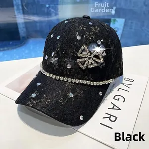 Close-up of black lace baseball cap with sparkling rhinestone bow and crystal chain