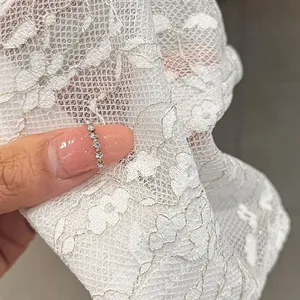 Close-up of minimalist silver band ring with micro-paved zircons on white lace fabric