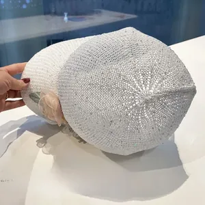Detail of white hollow knit cap with iridescent sequins and 3D mesh flower accent