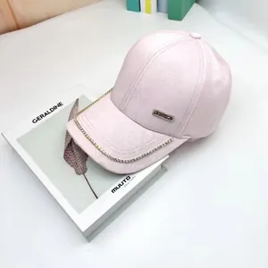 Pink baseball cap with embossed rose pattern and rhinestone brim detailing on a magazine
