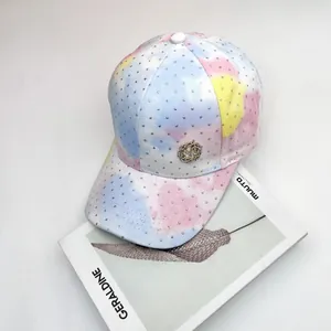 Gorra tie-dye con pedrería brillante y logo M de flores sobre libros de apoyo