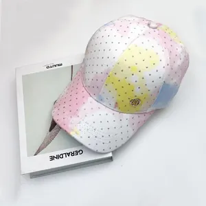 Detailed macro view of tie-dye baseball cap with sequins and rhinestone H logo badge