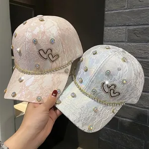 Detail view of lace baseball caps with rhinestones, pearls, and heart decorations
