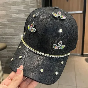 Dettaglio cappello baseball in pizzo nero con farfalle di strass e catena di diamanti