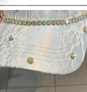 Dettaglio di pizzo floreale bianco su ecopelle argentata con catena di strass lucidi