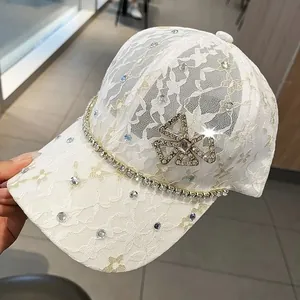 Close-up of white lace baseball cap with sparkling rhinestones and crystal bow detail