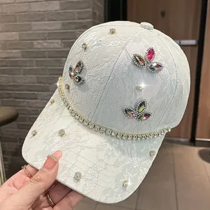 Dettaglio del cappellino in pizzo bianco con bordo in strass e farfalle di cristallo colorate