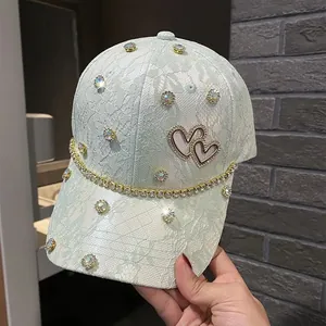 Detailed view of mint green lace baseball cap with sparkling rhinestone heart and trim
