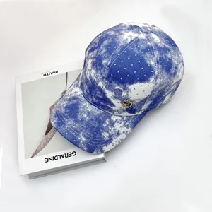 Close-up of blue and white tie-dye baseball cap with sparkling rhinestones and metal logo