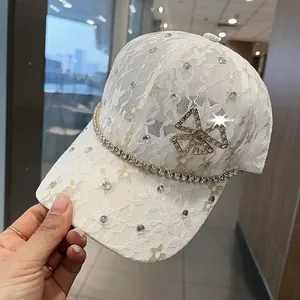 Close-up of white lace baseball cap with sparkling rhinestones and a crystal bow accent