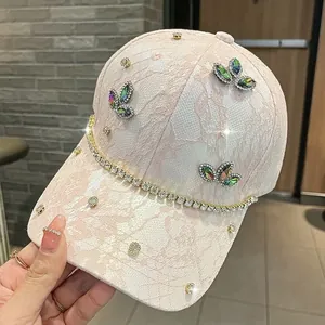 Dettaglio del berretto rosa in pizzo con strass e farfalla di pietre preziose colorate
