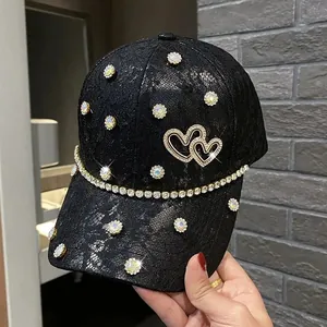 Detailed view of black lace baseball cap with sparkling rhinestone heart and floral accents