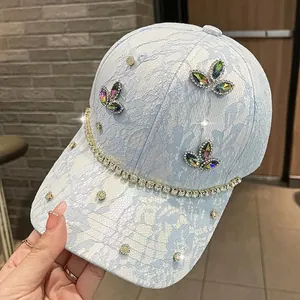 Dettaglio cappello in pizzo azzurro con farfalle di strass e visiera con cristalli
