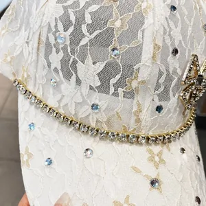 Detail of ivory lace baseball cap with sparkling rhinestones and floral embroidery