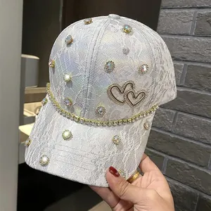 Detail of white lace baseball cap featuring iridescent rhinestones and double heart decor