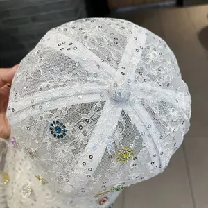 Detail einer weißen Spitzen-Baseballkappe mit bunten Strassblumen und silbernen Pailletten