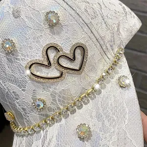 Close-up of white lace baseball cap featuring rhinestones and heart-shaped crystals