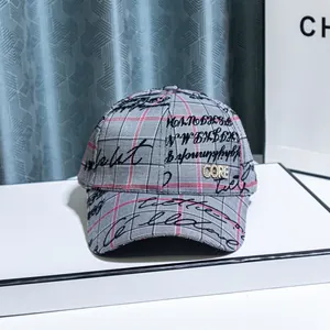 Detail of grey plaid baseball cap featuring rhinestone letter logo and black script print