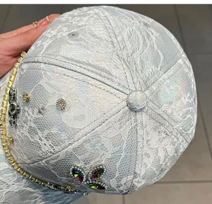 Dettaglio del cappellino in pizzo olografico bianco con farfalle di strass colorati brillanti