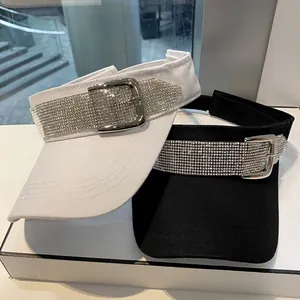 Detail van zwart-witte zonnekleppen met fonkelende steentjes en metalen gespen
