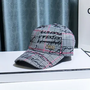 Gray and pink plaid baseball cap with sparkling rhinestone CORE logo on a white surface