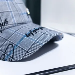 Detailed macro view of gray and blue plaid twill baseball cap with black embroidered text
