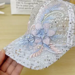 Detailed view of floral lace embroidery and pearl accents on the white sequin mesh cap