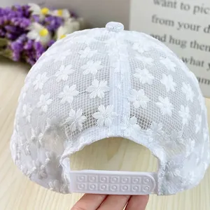 Detail of white lace baseball cap featuring daisy embroidery and adjustable snapback strap