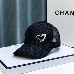 Detail view of rhinestone heart and 3D floral accents on black lace baseball cap