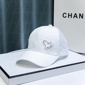 Close-up of white lace baseball cap with rhinestone heart and mesh back panel