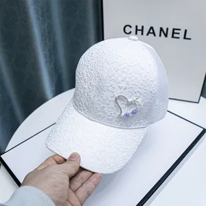 Detailed view of white lace baseball cap with rhinestone heart and floral accents