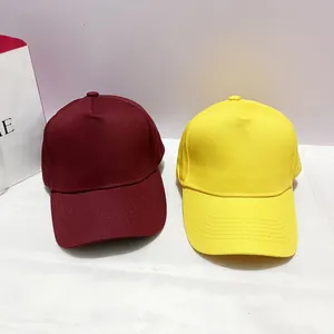 Flat lay of minimalist burgundy and yellow cotton twill baseball caps on a desk