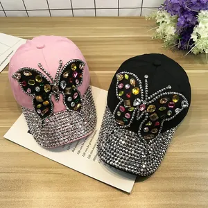 Détail de deux casquettes avec de grands papillons en cristal et des visières en strass