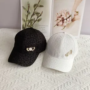 Black and white women baseball caps with textured fabric and rhinestone heart floral detail