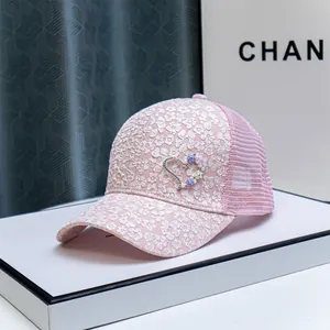 Detail of pink baseball cap featuring white flower embroidery and rhinestone heart