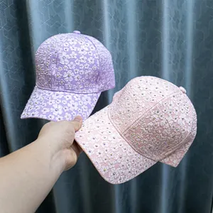 Detail of pink and purple baseball caps featuring 3D floral embroidery and rhinestones